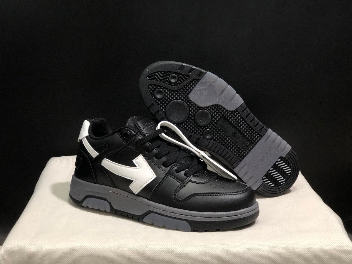 Angled view of one black sneaker with its textured black-and-gray outsole visible behind it.