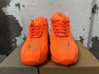 Front view of bright orange lace-up sneakers with mesh panels.