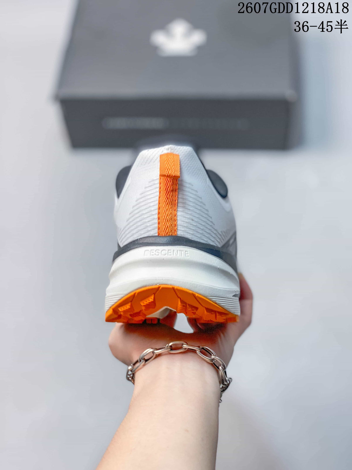 Rear view showing the white heel, navy collar trim, orange pull tab, and orange outsole.