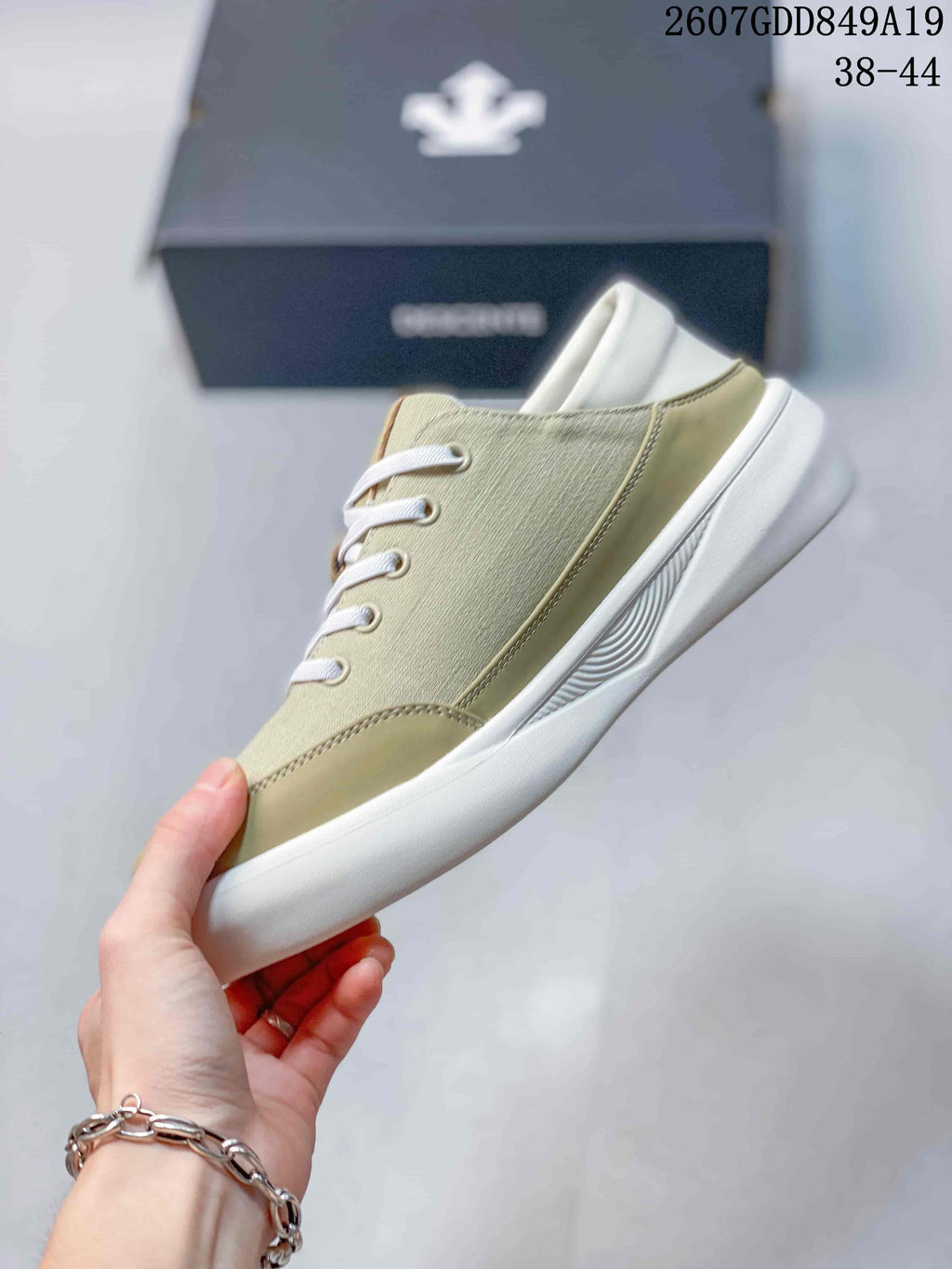 Side profile of the beige low-top sneaker showing the textured upper, stitched panels, white laces, and white sole.