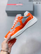 Side view of the low-top sneaker showing glossy orange panels, gray inserts, white laces, and a white flat sole.