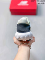 Rear view of a white New Balance sneaker showing the black padded heel collar, Fresh Foam heel branding and sculpted outsole; a red New Balance shoe box is in the background.
