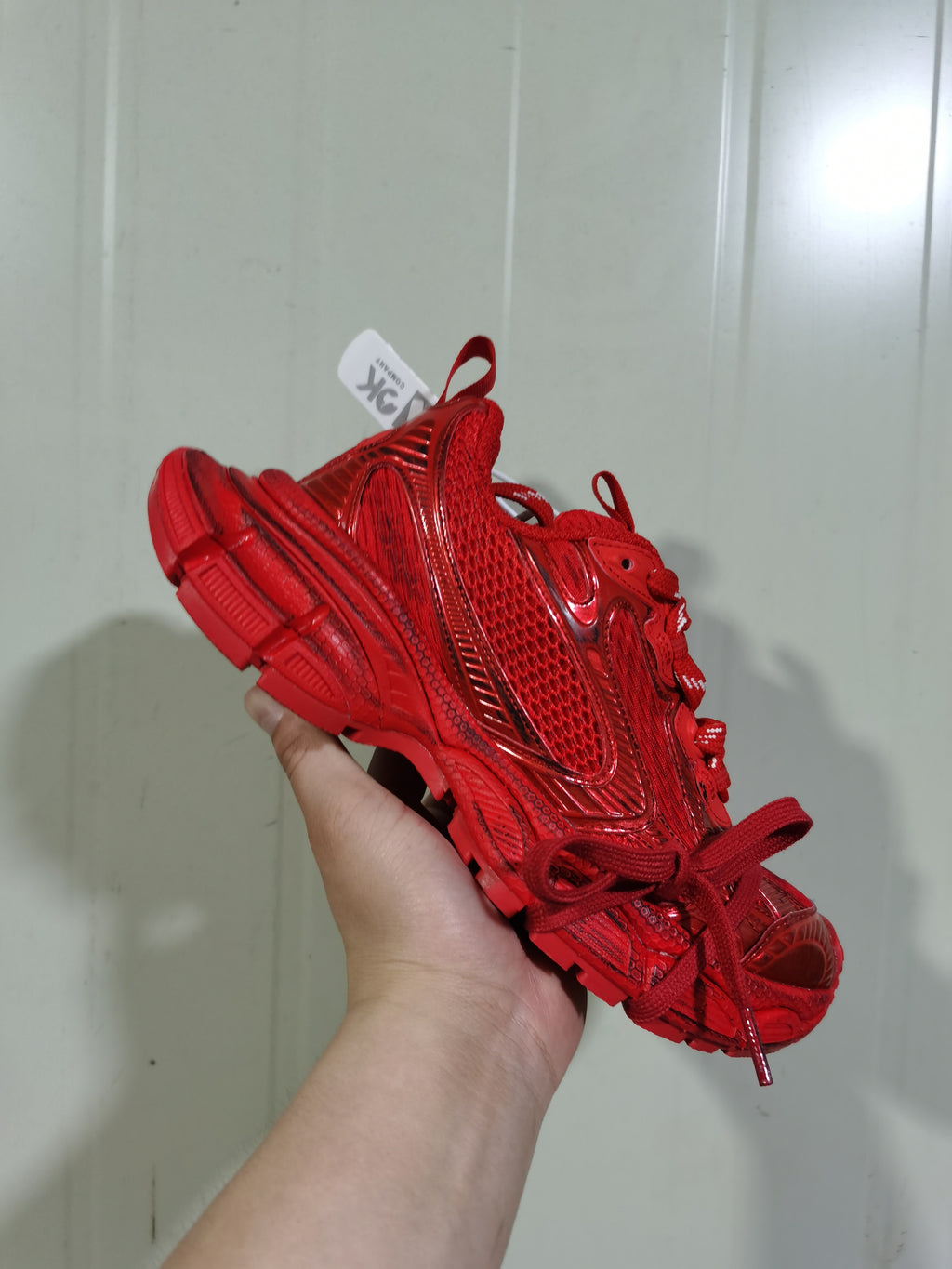 Rear-side view of the red sneaker showing the textured heel, pull tab, layered side panels, and segmented outsole.