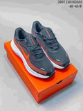 Pair of charcoal and orange Nike Vomero low-top running shoes on an orange shoebox