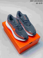 Pair of charcoal and orange Nike Vomero low-top running shoes on an orange shoebox