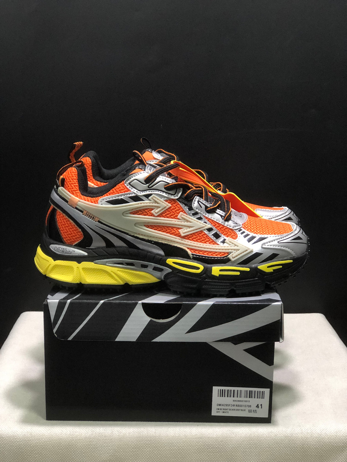 Side view of the orange and silver Off-White Be Right Back sneakers with black detailing and yellow outsole accents.