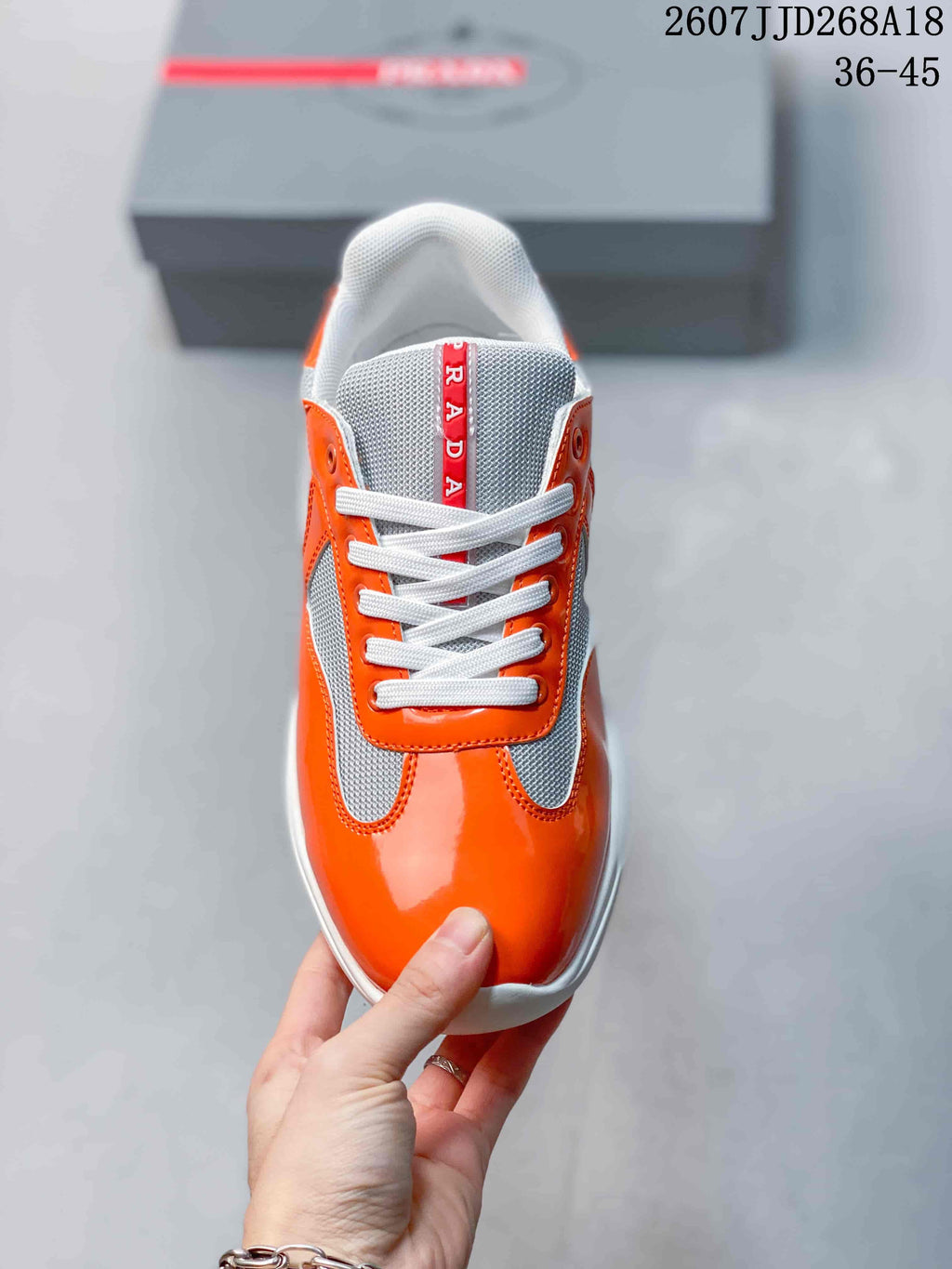 Top view of the sneaker showing the rounded orange toe, gray tongue, white laces, and vertical branding detail.