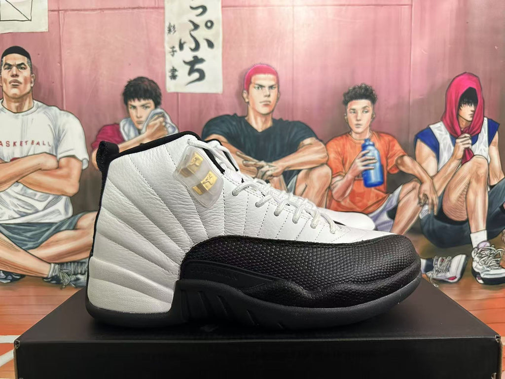 Side view of a white Jordan 12 sneaker with a black textured mudguard and gold-tone detail.