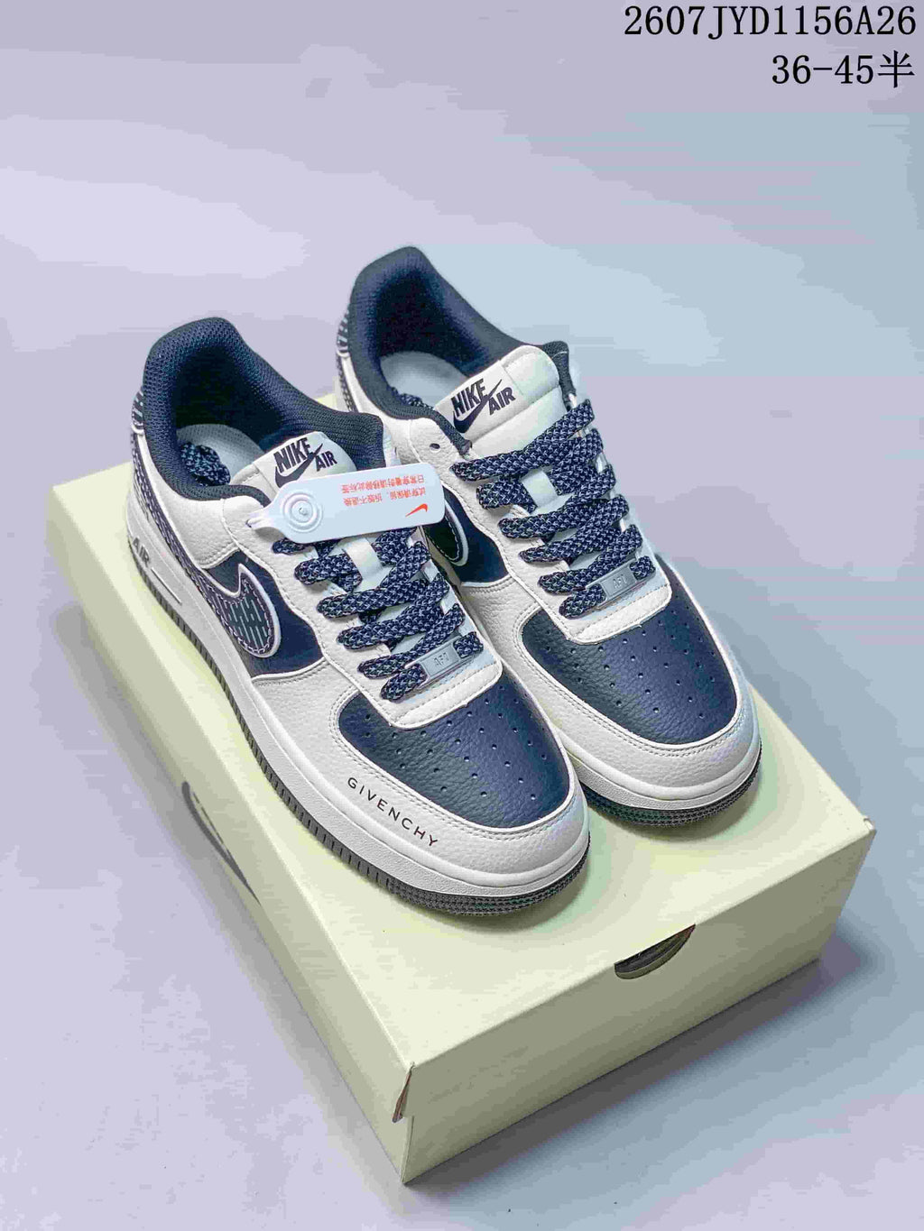 Pair of white and navy Nike Air Force 1 low-top sneakers displayed on a shoebox, with dark laces and visible side graphics.