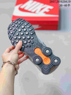 Close-up of the black outsole with circular traction elements and orange accents on a Nike Shox Ride 2 sneaker.