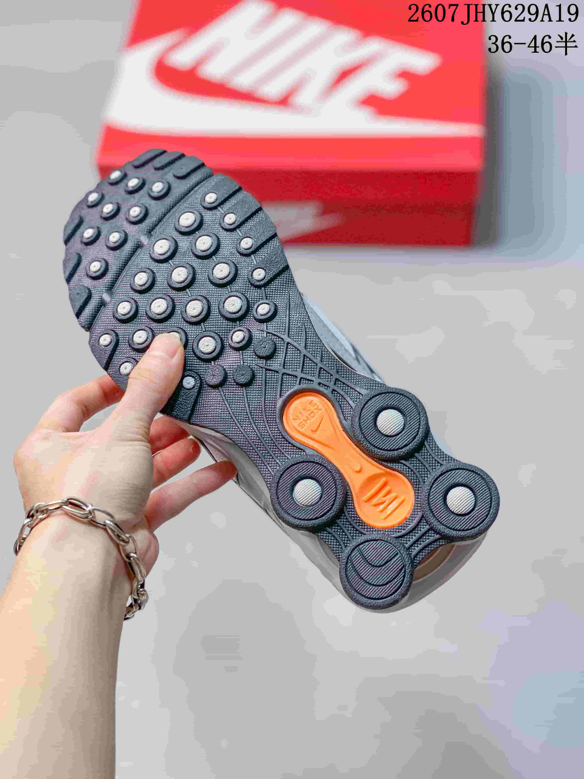 Close-up of the black outsole with circular traction elements and orange accents on a Nike Shox Ride 2 sneaker.