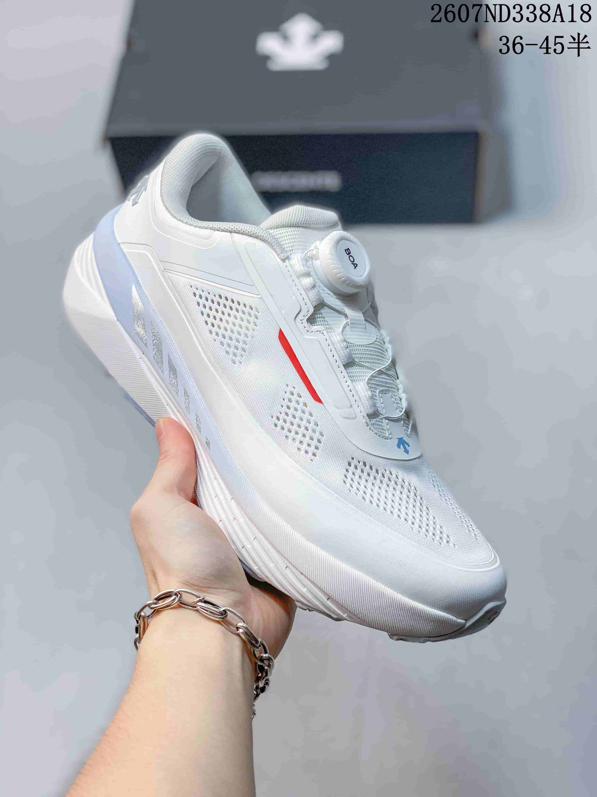 Close side view of a white Descente sneaker showing the perforated upper, red accent detail and sculpted sole.