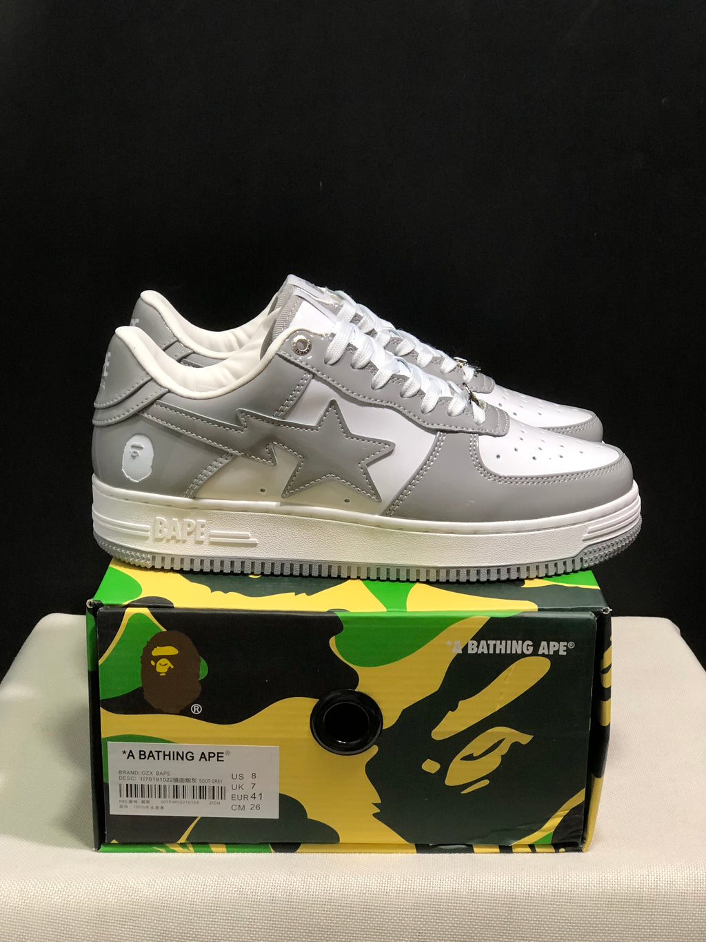 Side view of a white and grey BAPE Sta sneaker with a star-shaped side logo and branded camouflage shoebox.
