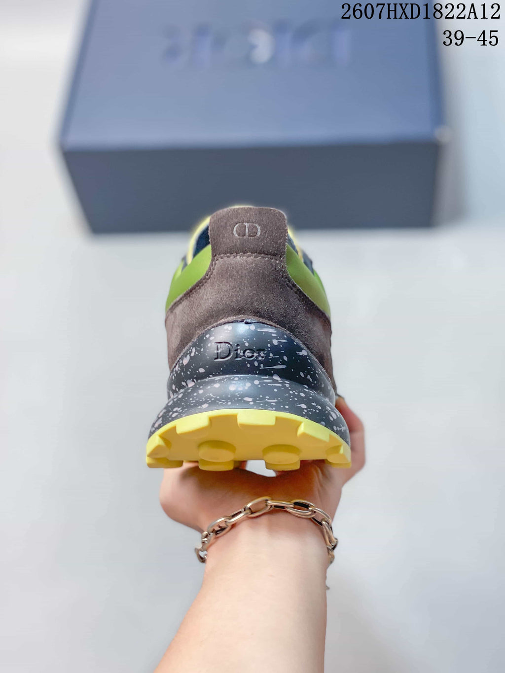 Rear view of the sneaker showing the brown heel panel, Dior branding, speckled midsole, and yellow outsole.