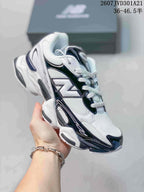 Angled side view of a white, navy, and black New Balance 9060R sneaker held in hand.