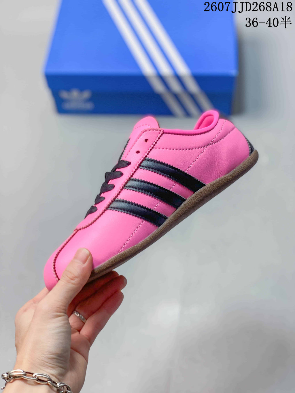 Side profile of the pink low-top sneaker showing black stripes, stitching, and the gum-colored sole.