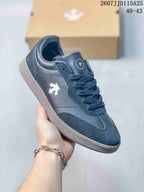 Angled side view of the Descente sneaker showing the side emblem, lace-up closure and low-top shape.