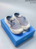 Pair of gray and cream HOKA Ora Primo EXT mule-style shoes on a blue box