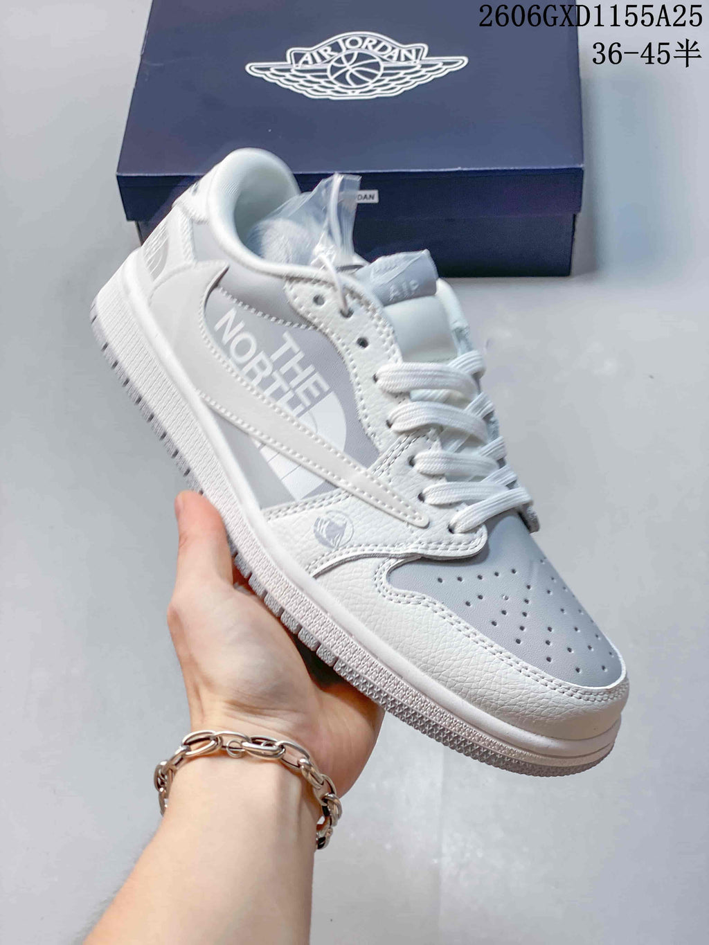 Angled view of a white and light grey sneaker with graphic side branding and perforated toe.