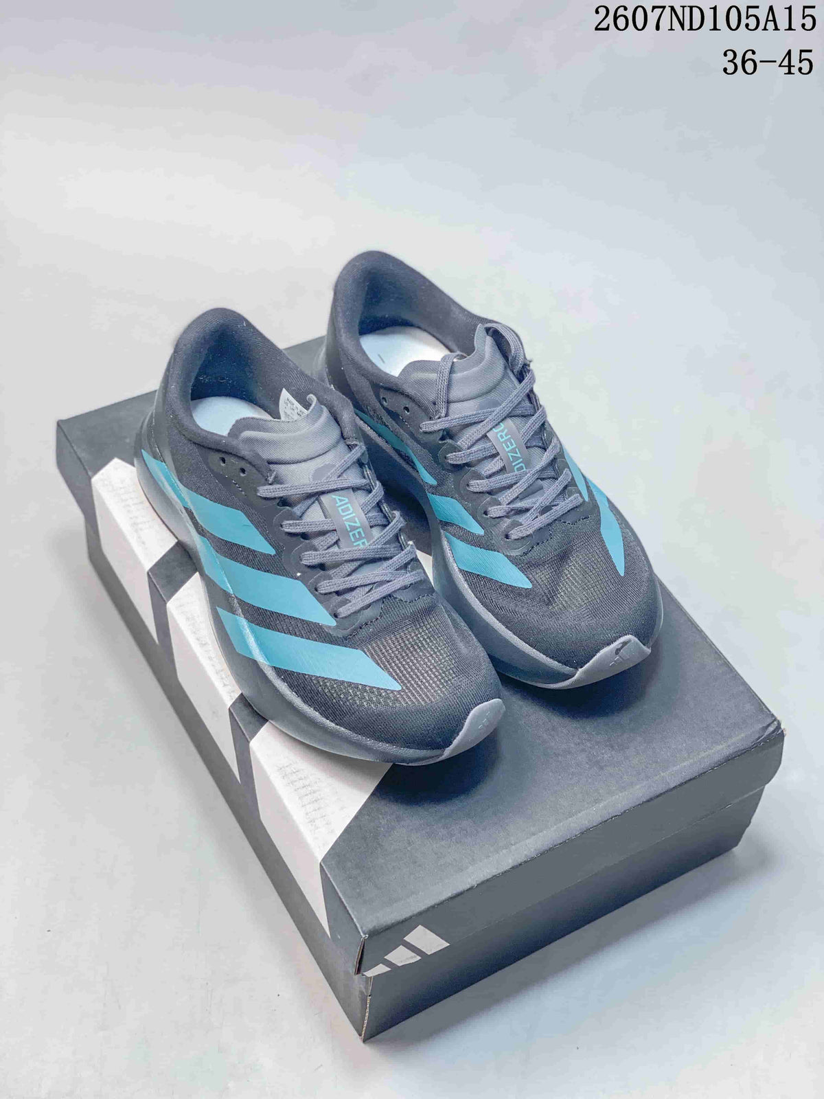 Dark gray Adidas Adizero sneakers with teal contrast stripes displayed on a shoebox.