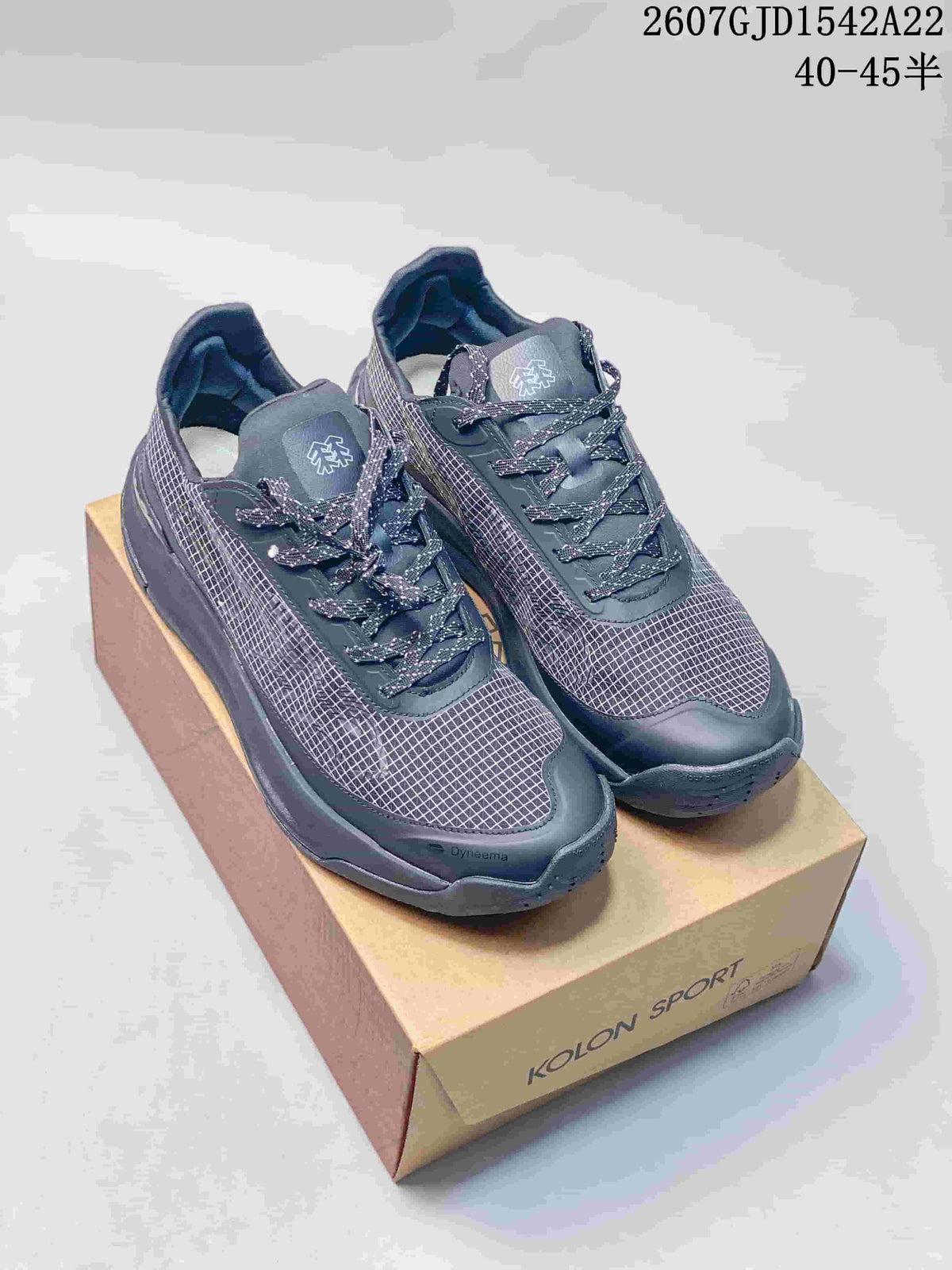 Pair of dark charcoal KOLON SPORT low-top hiking shoes displayed on a branded shoebox; image text shows style code 2607GJD1542A22 and size range 40–45.
