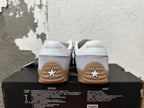 Rear view of gray Converse trainer-style sneakers with white heel panels and gum-colored soles