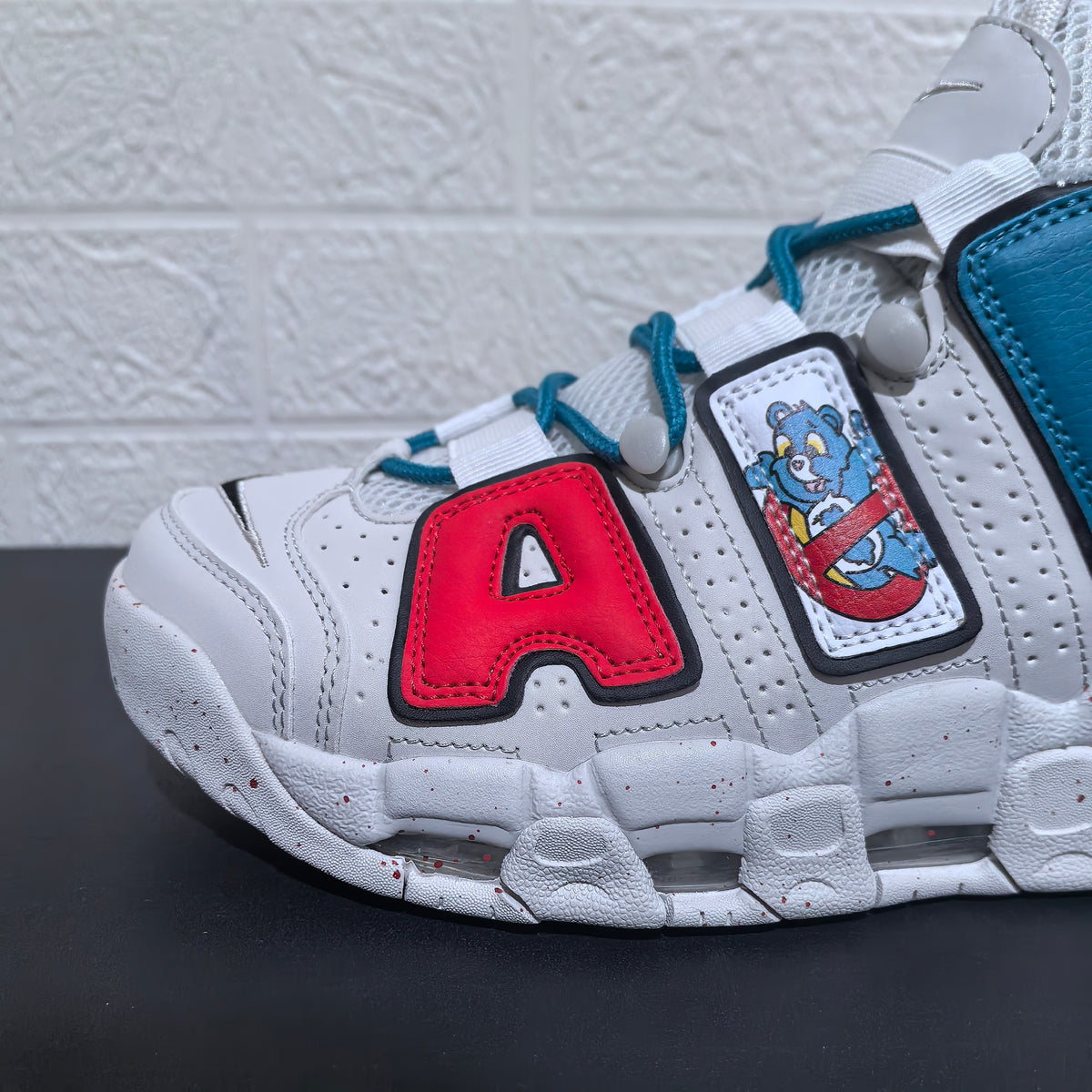 Close-up of the white and red upper, teal laces and cartoon bear patch