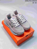 Pair of mauve-gray Nike sneakers with white laces displayed on an orange shoebox