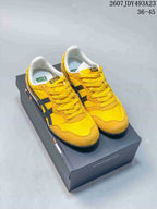 Yellow Onitsuka Tiger Serrano sneakers with dark contrast stripes displayed on a shoe box.