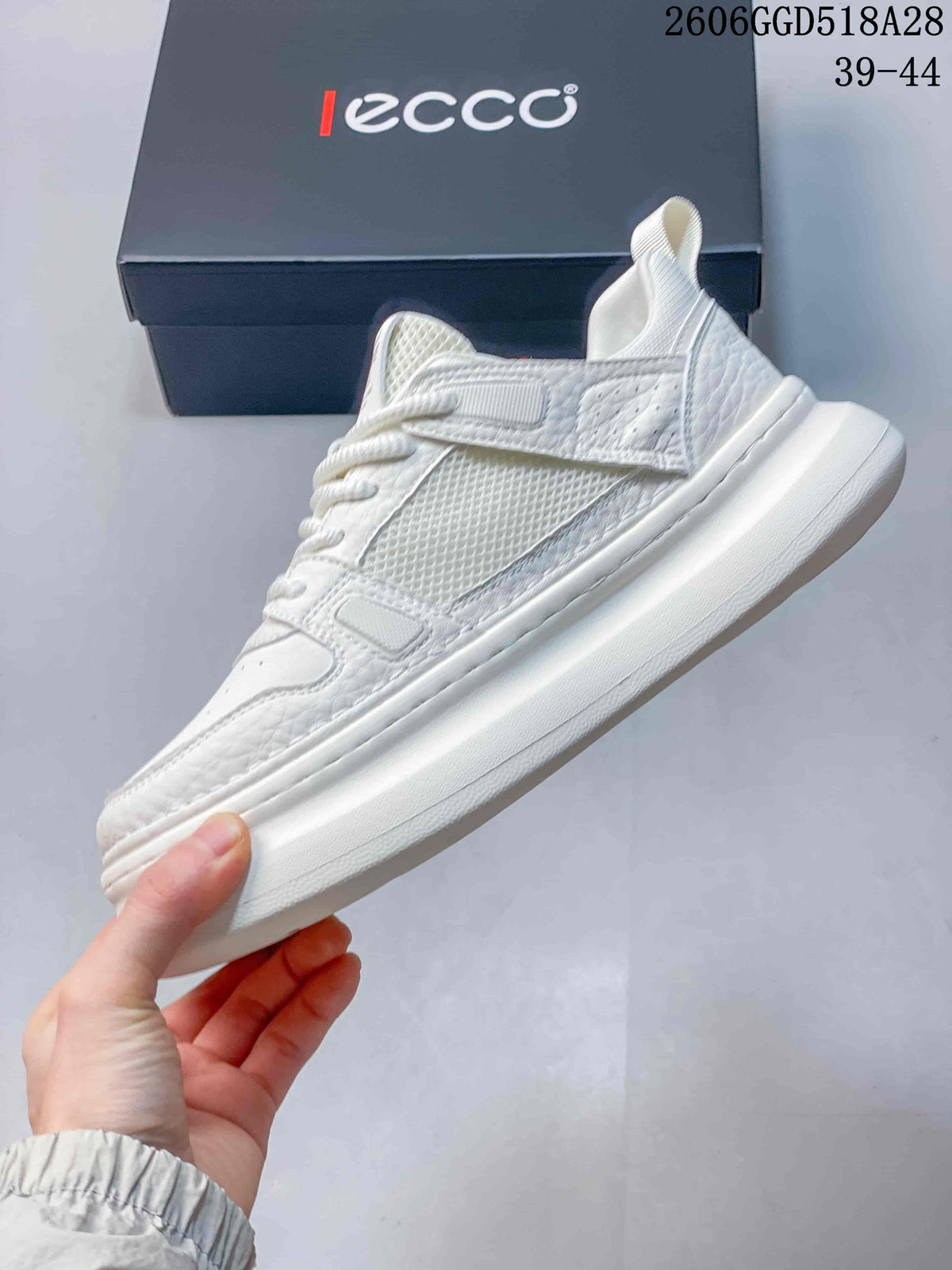 Side view of the white sneaker showing mesh panels, strap detail, and raised sole.