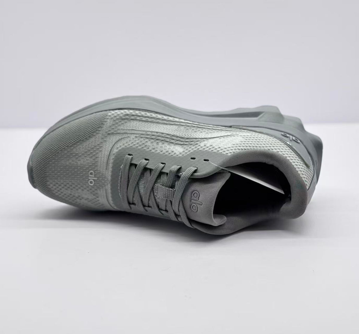 Top-down view of one gray sneaker highlighting the laces, tongue logo, collar, and textured upper.
