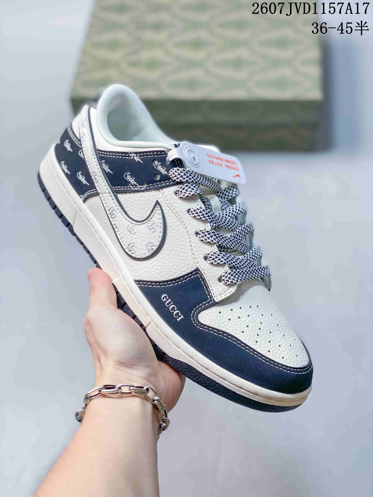 White and navy low-top sneaker with patterned overlays, contrasting laces, and visible Gucci-style lettering.