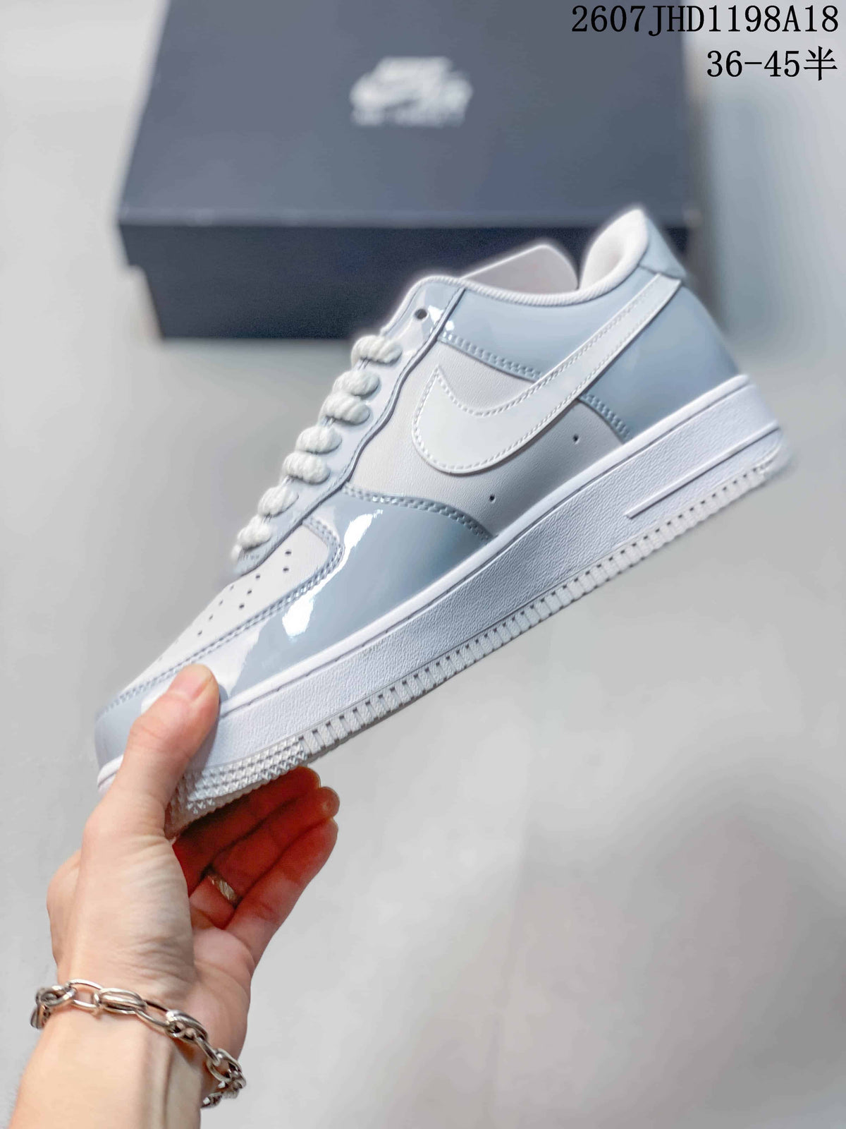 Side view of the gray and white sneaker showing the white Swoosh, layered panels, laces, and rubber sole.