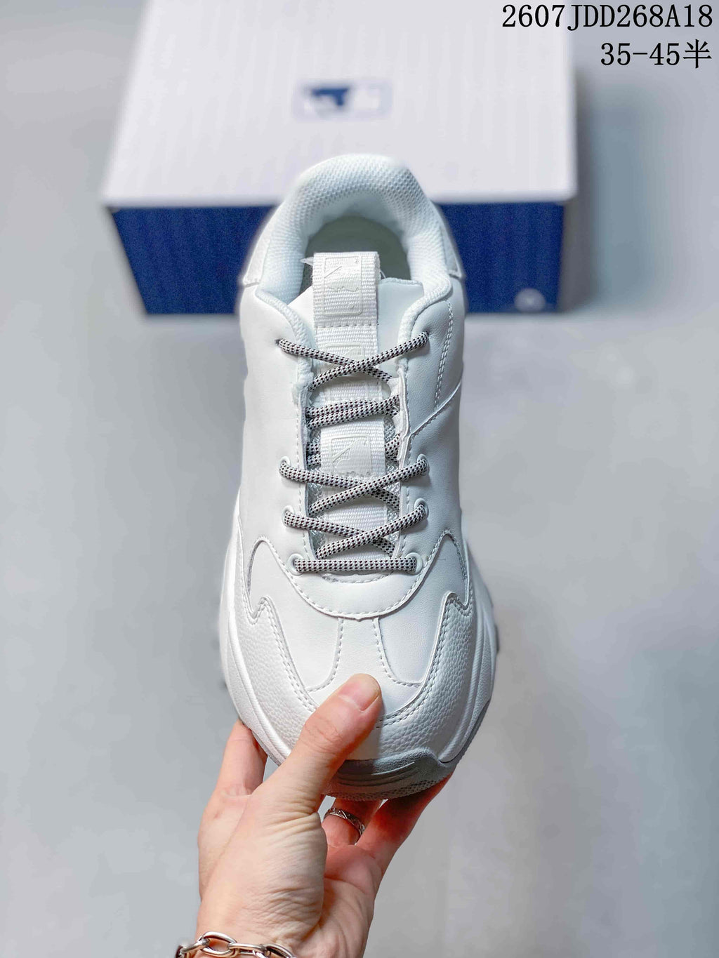 Top view of the white sneaker showing the padded collar, tongue, patterned laces and layered toe construction.