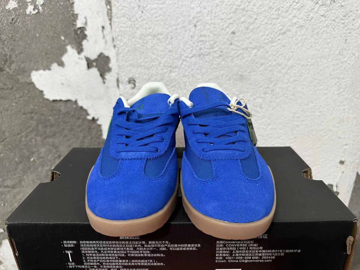 Front view of blue lace-up Converse training-style shoes with gum-colored soles