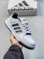 White adidas Entrap sneaker with black side stripes, red tongue branding and a dark outsole.
