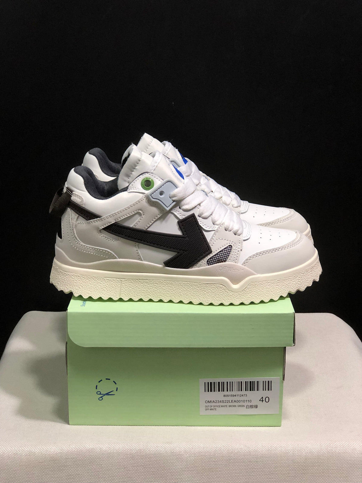 Side view of the white sneakers showing the black arrow detail, layered panels, and textured outsole.