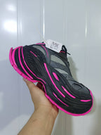 Close-up view of grey and black New Balance sneakers with bright pink trim and outsole accents.