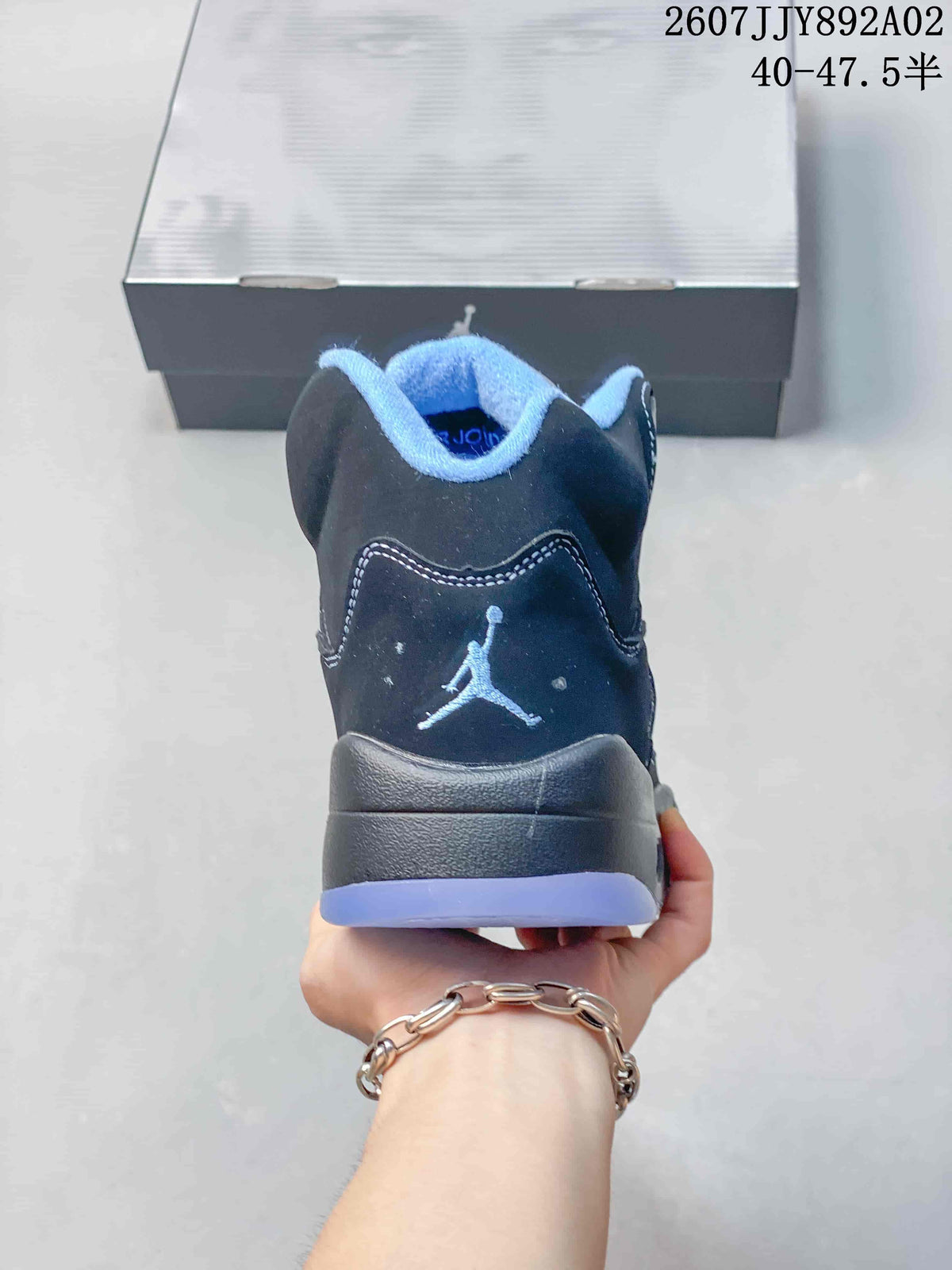 Rear view of the dark low-top sneaker with a light blue collar and heel logo