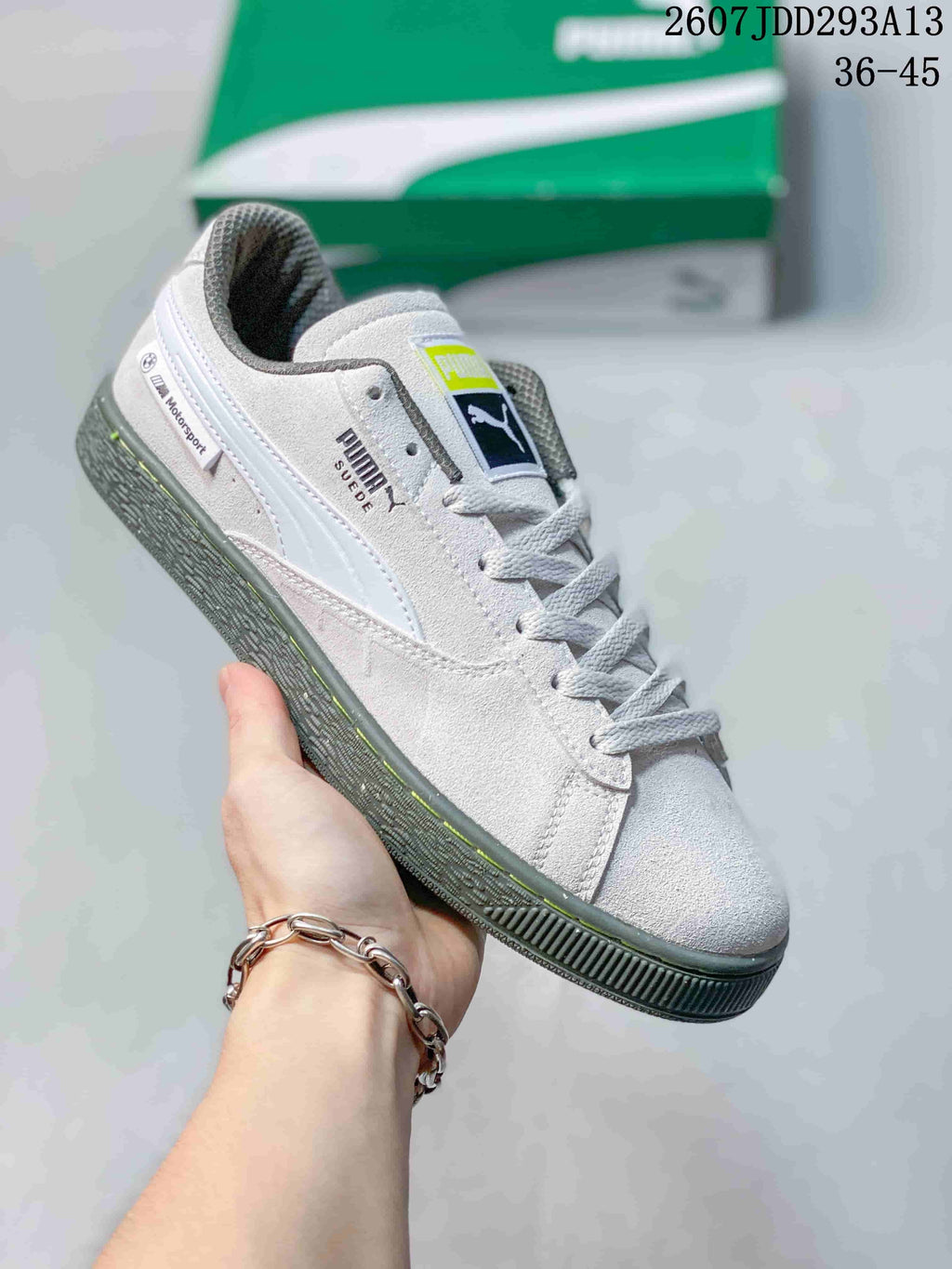 Angled side view of the white PUMA sneaker showing BMW Motorsport text, PUMA branding, gray accents, and the textured outsole.
