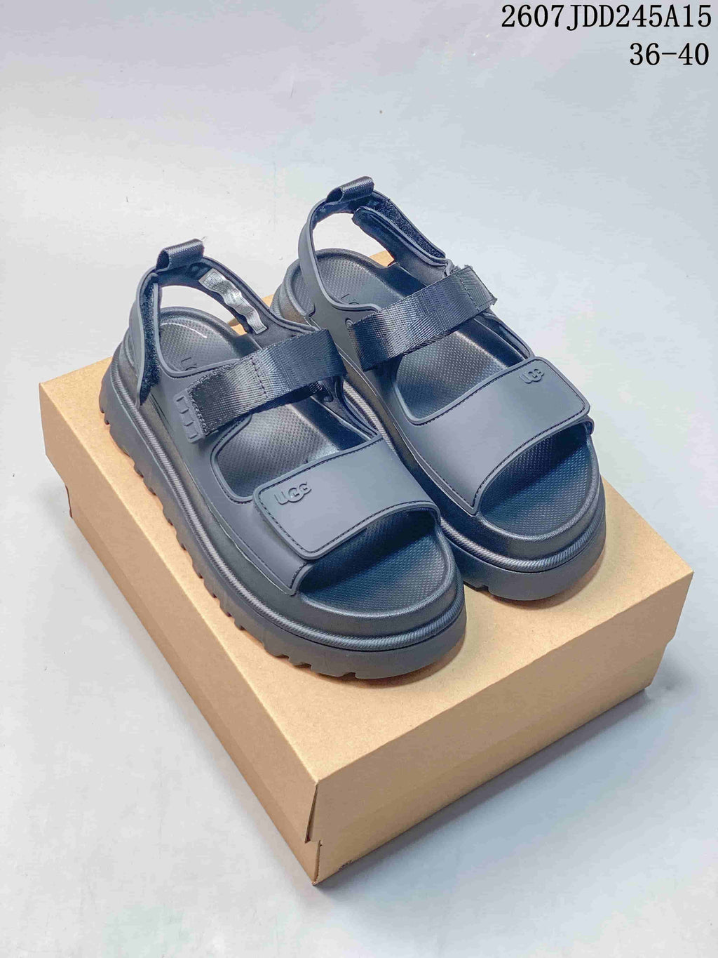 Pair of black UGG GoldenGlow sandals displayed on a cardboard box, with the product code 2607JDD245A15 and size range 36–40 visible.