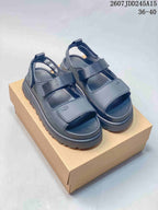 Pair of black UGG GoldenGlow sandals displayed on a cardboard box, with the product code 2607JDD245A15 and size range 36–40 visible.
