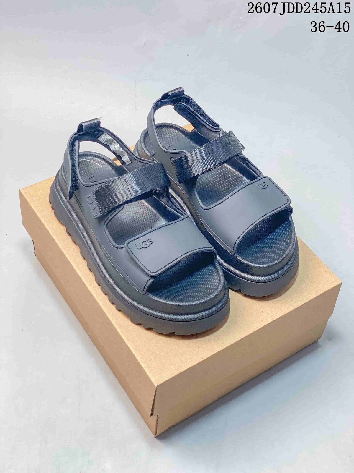 Pair of black UGG GoldenGlow sandals displayed on a cardboard box, with the product code 2607JDD245A15 and size range 36–40 visible.