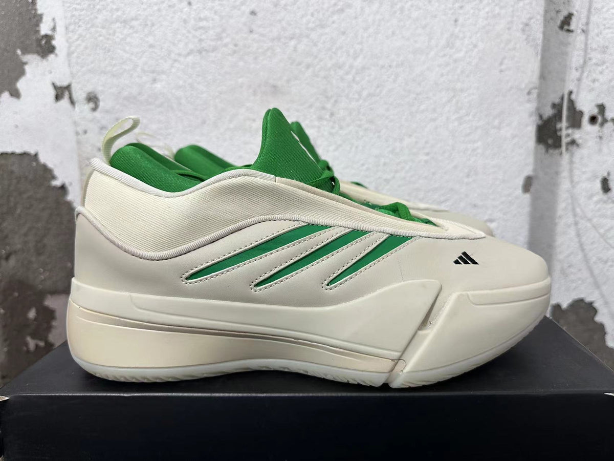 Side view of a cream Dame 9 shoe with green accents