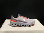 Side profile of a gray On Cloud X sneaker showing the sculpted sole and orange heel accent.