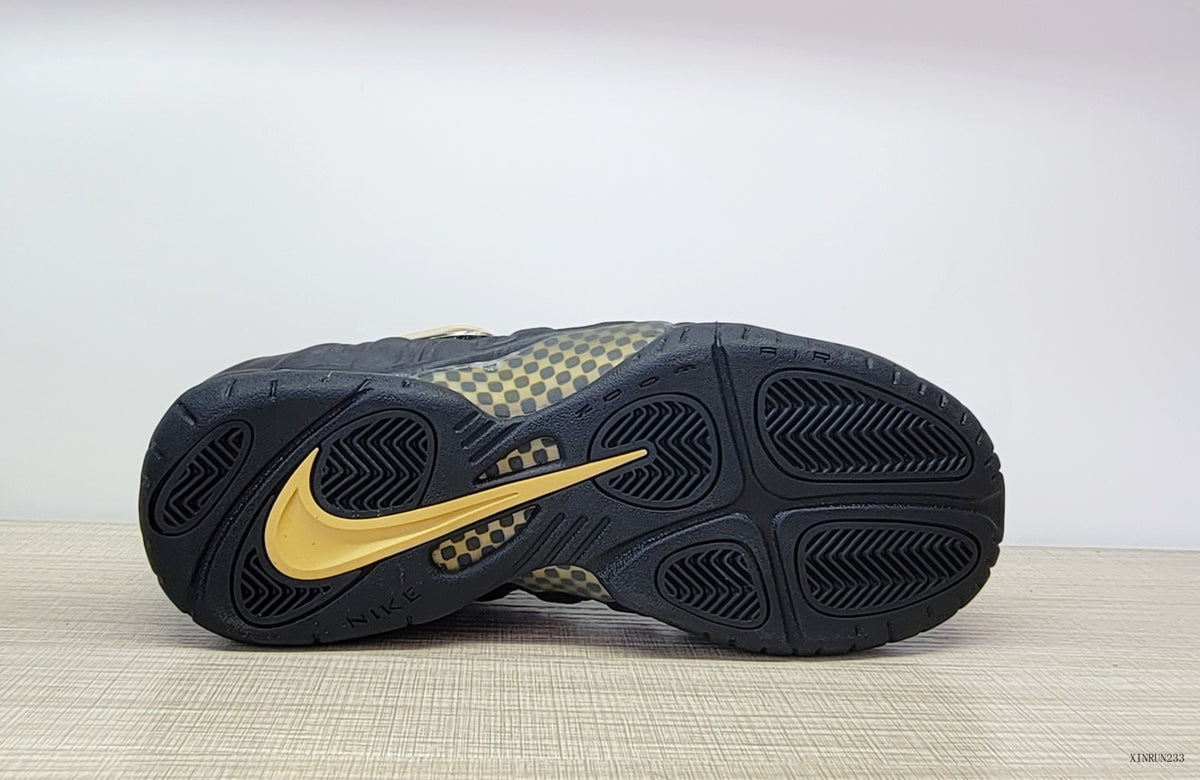 Outsole view showing black tread and gold detailing on the Nike Air Foamposite Pro