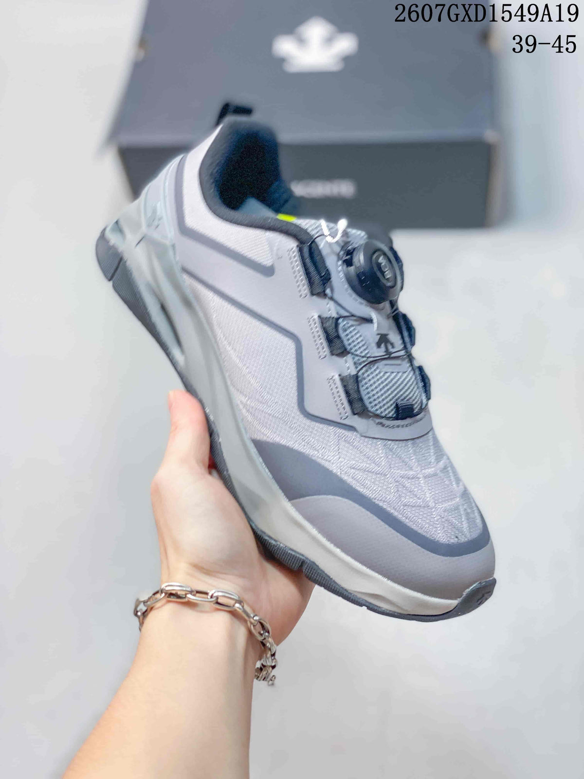 Angled side view of the gray and white DESCENTE sneaker showing the BOA dial, mesh-like upper panels, and layered sole.