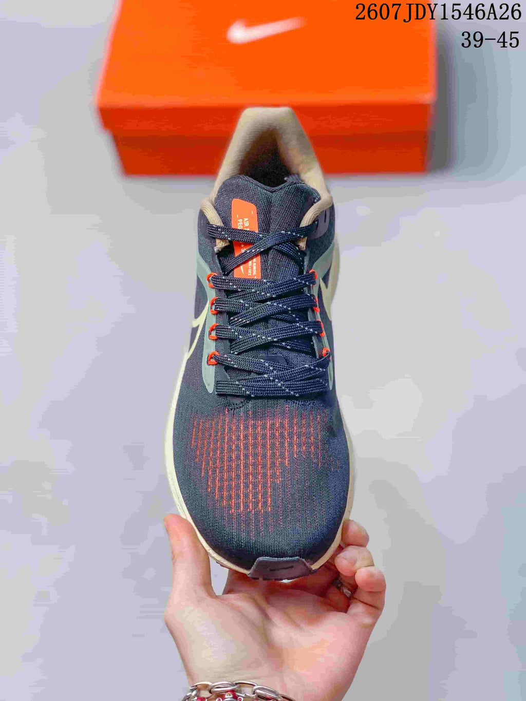 Top view of the lace-up sneaker showing the navy upper, orange tongue label, and orange-accented forefoot details.