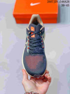 Top view of the lace-up sneaker showing the navy upper, orange tongue label, and orange-accented forefoot details.