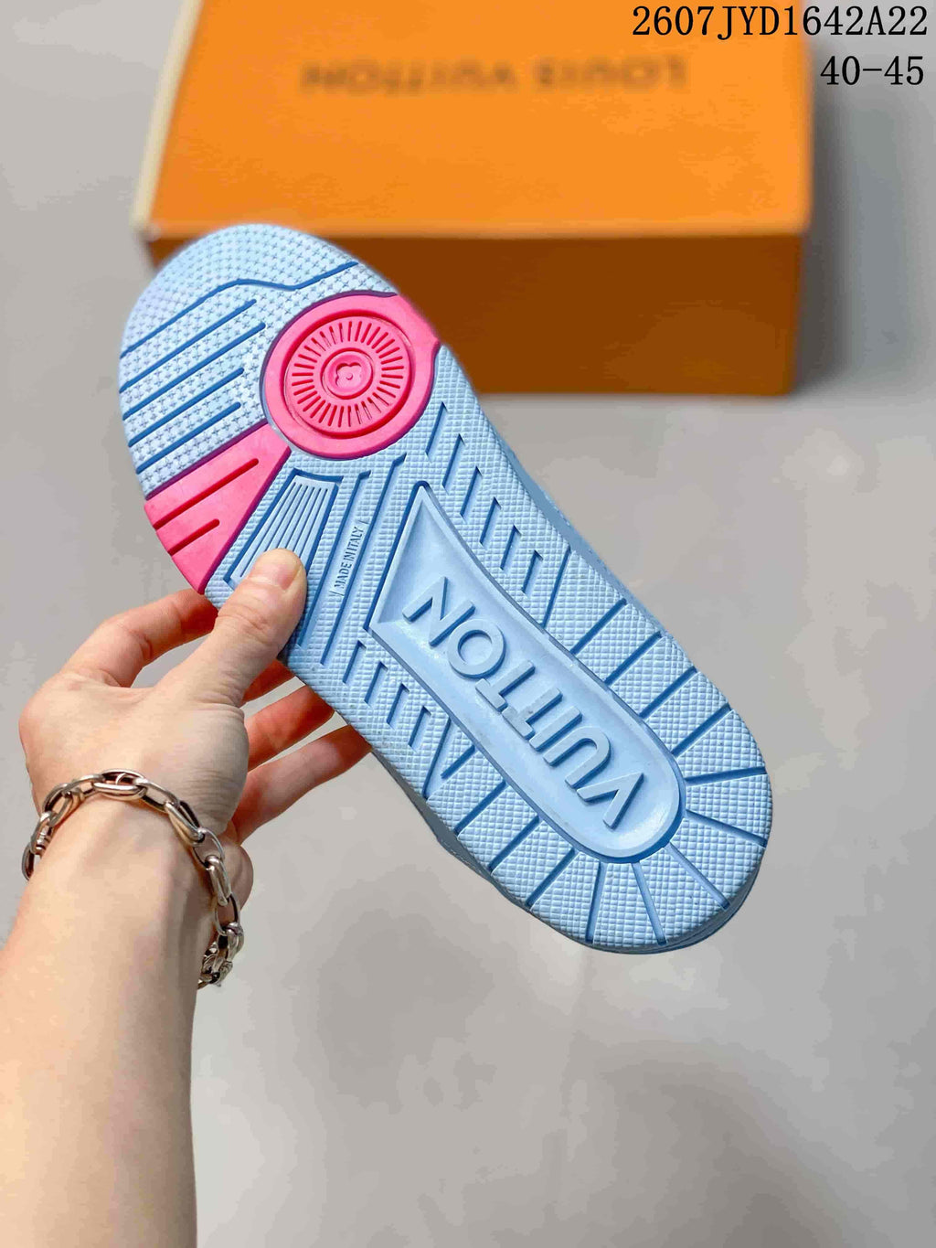 Underside of a light blue sneaker showing the textured rubber outsole, pink circular accent, and molded Louis Vuitton branding.